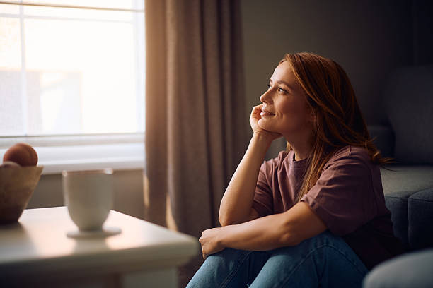 istock Smiling woman day dreaming while enjoying in day at home. 2235739940