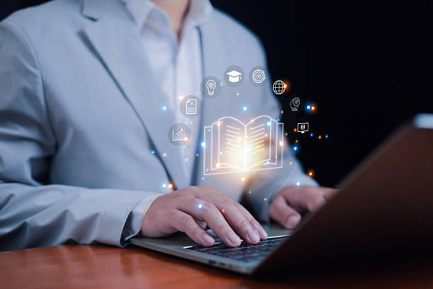 istock Businessman typing on laptop with digital book and education icons, e-learning technology, online training, knowledge sharing, innovation, academic growth, and modern digital education concept. 2235741690
