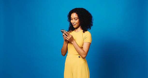 istock Phone, happy and woman in studio with networking, communication or texting on mobile app. Mockup space, technology and person with cellphone for chatting, contact or social media by blue background. 2235745299