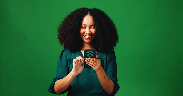 istock Phone, smile and scroll with woman in studio for social media, networking or connection. Mockup space, text message and search with person on green background for contact, typing or communication app 2235745427