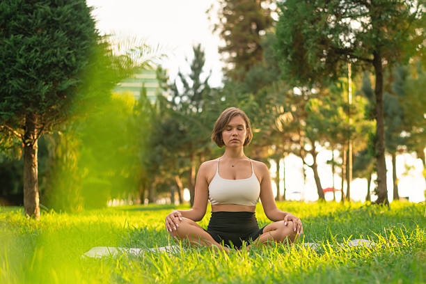 istock Young woman meditating outdoors 2235748446