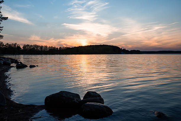 Serene sunset over tranquil lake with scenic shoreline and reflective waters.