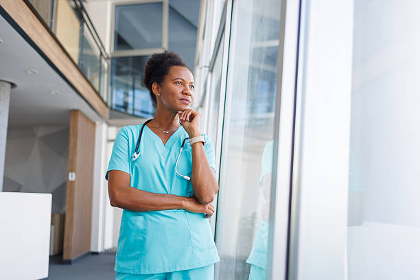 istock Thoughtful doctor looking out window in modern hospital 2235752032