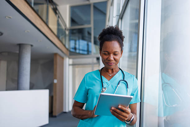 istock Smiling doctor using digital tablet in hospital corridor 2235752143