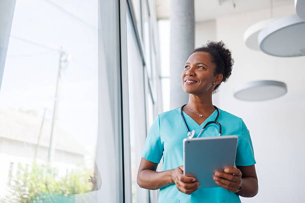 istock Smiling doctor looking out window holding digital tablet in hospital 2235752155
