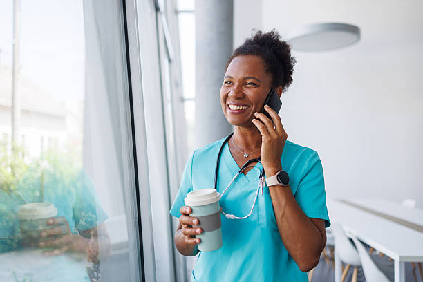 istock Smiling doctor drinking coffee and talking on phone during break 2235752182