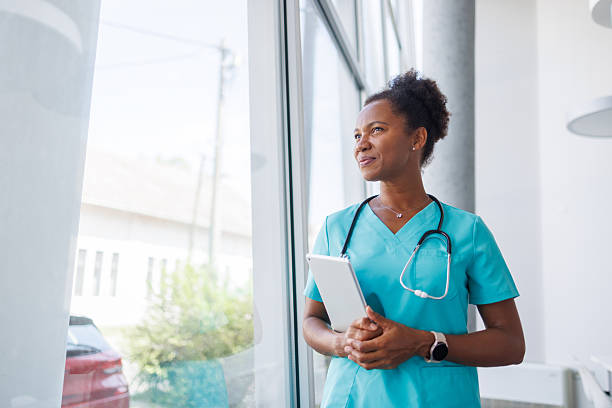 istock Confident mid adult doctor looking out window holding digital tablet 2235752191