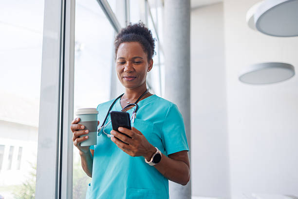 istock Smiling doctor drinking coffee and using smartphone in hospital corridor 2235752305