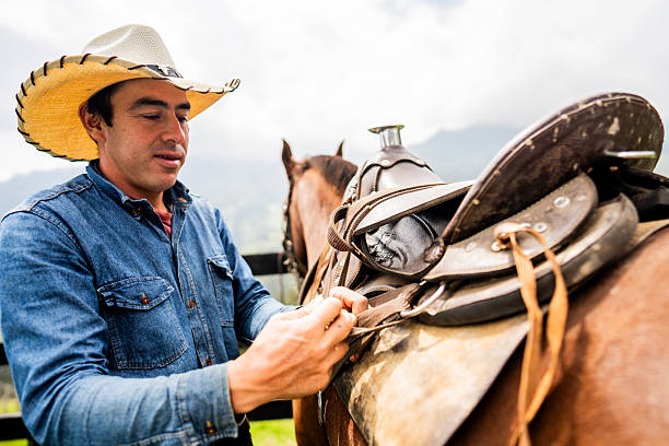 Farmer man putting saddle on horse on a farm