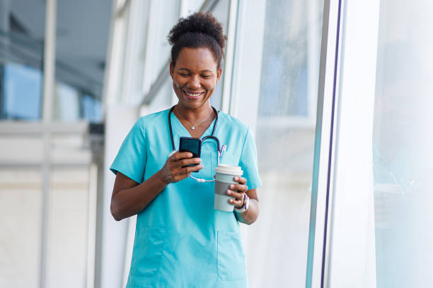 istock Smiling doctor using smartphone and holding coffee in hospital corridor 2235752507