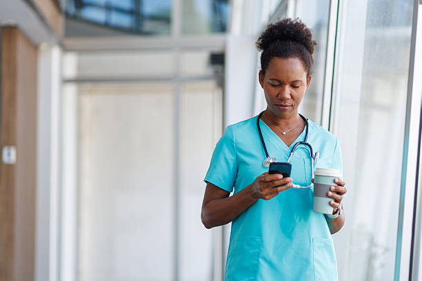 istock Doctor using smartphone and holding coffee in hospital corridor 2235752522