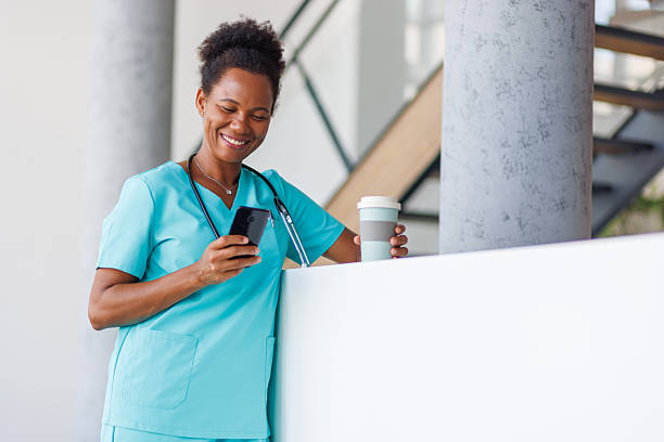 istock Smiling doctor using smartphone and drinking coffee during break 2235753173