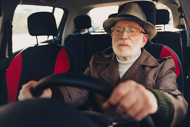 istock Elderly man in a stylish hat driving a car outdoors during a sunny fall day 2235753691
