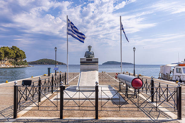 Skiathos, Greece – 5 September 2025: Memorial dedicated to the crew of the Greek submarine Katsonis, which was sunk during World War II in 1943. The monument, located at the old port of Skiathos, features the bust of submarine commander Vasileios Laskos, a torpedo display, and two Greek flags. The memorial lists the names of the fallen crew and serves as a site of annual remembrance.