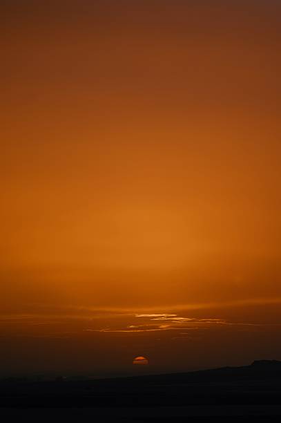 A stunning sunset over a dark horizon with a vibrant orange sky creating a serene and peaceful atmosphere.