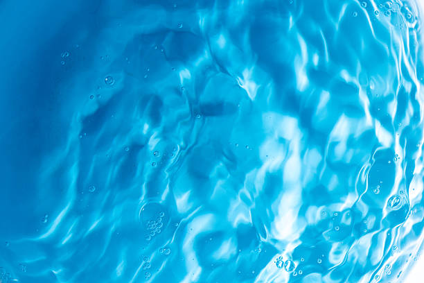 istock Transparent blue clear water surface texture with ripples, splashes and bubbles. Abstract summer banner background Water waves in sunlight with copy space Cosmetic moisturizer micellar toner emulsion 2235756051