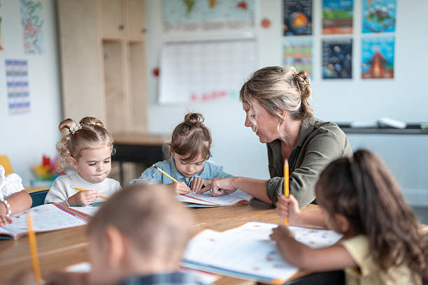 istock Teacher Helping Kindergarten Students With Writing Lessons in Classroom 2235758039