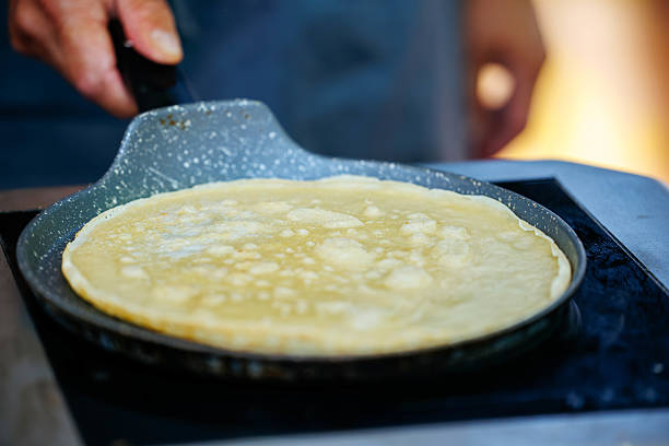 Golden crepe cooking in pan on stovetop at kitchen