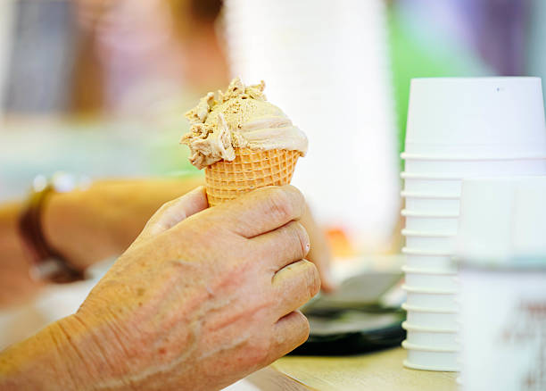 istock Mature caucasian hands holding a chocolate ice cream cone in a waffle cone 2235758348