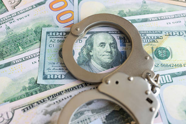 istock Handcuffs lying on american dollars 2235758508