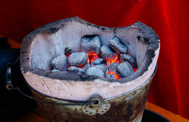 istock Glowing charcoal in rustic metal brazier against red background 2235758723