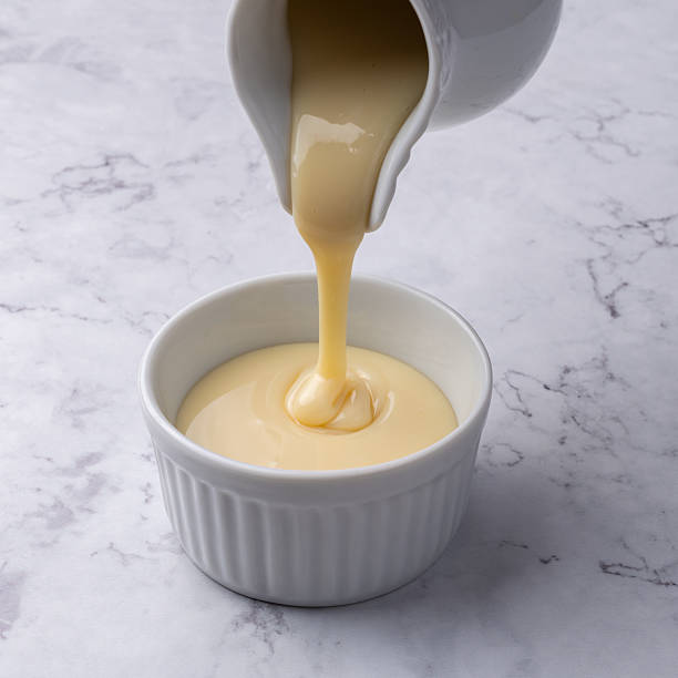 istock Pouring condensed milk in a bowl over marble background 2235758879