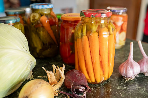 Assorted pickled vegetables with fresh produce on kitchen counter.