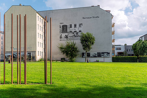 View of the Berlin Wall Memorial at Bernauer Strasse, showcasing symbolic steel pillars and a historic photograph mural, representing cultural heritage and the division's historical significance.