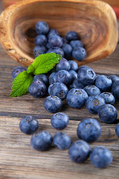 Blueberries with mint leaves scattered from basket on wooden rustic table