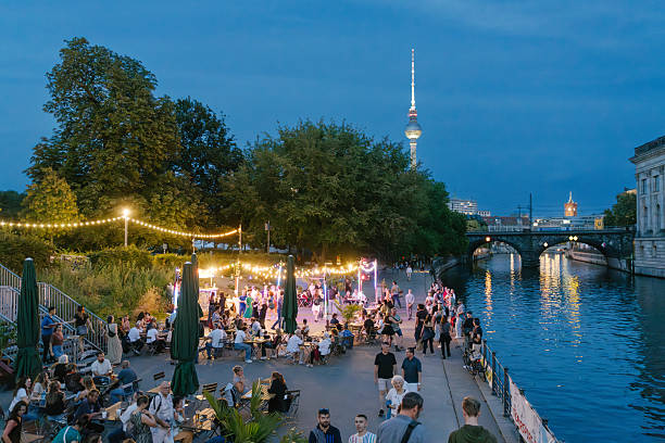 Evening Outdoors in a Berlin Riverside Park with Relaxed Crowds and Festive Lights