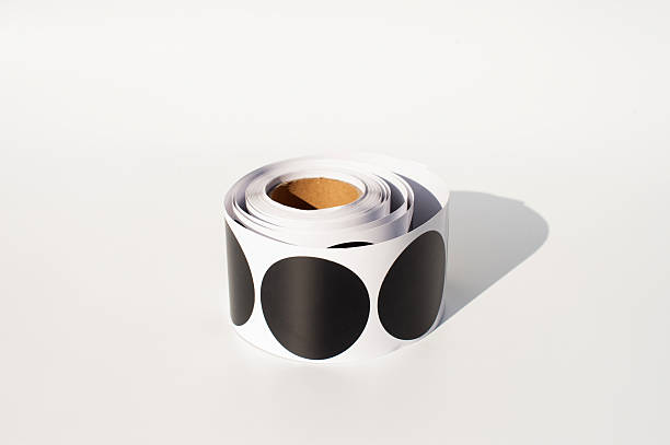 Roll of large round black stickers on white background