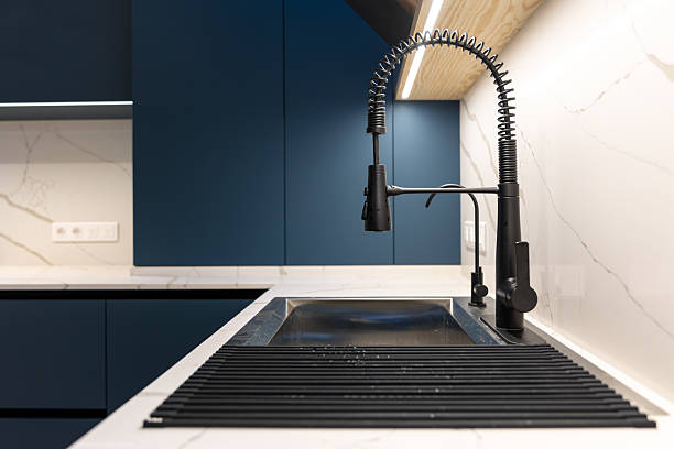 istock Matte black kitchen faucet and sink with drying rack in blue kitchen. Minimal interior. 2235763196