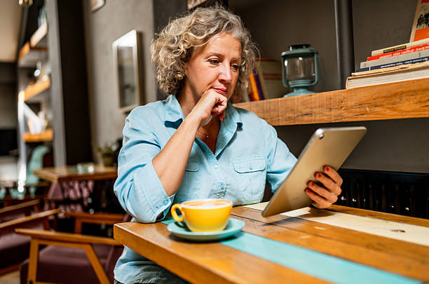 istock Mature woman using digital tablet in cafe 2235767343