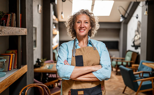 istock Mature waitress smiling with crossed arms in cafe 2235768624