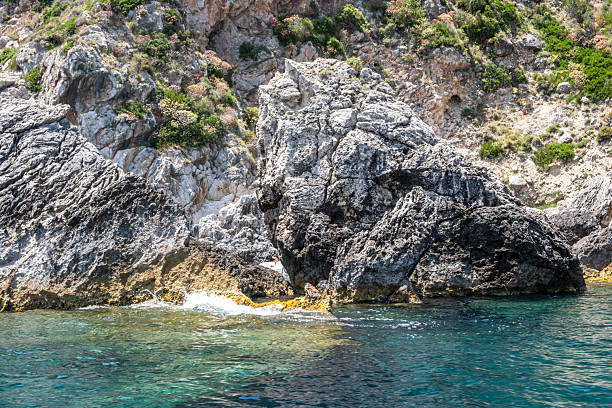 istock Steep rocky cliffs rise from the clear turquoise sea, sunlight reflections on the rippling water, Corfu island Greece 2235772101