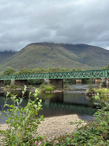 istock Serene Scenic Bridge with Mountains and Lush Greenery 2235772802
