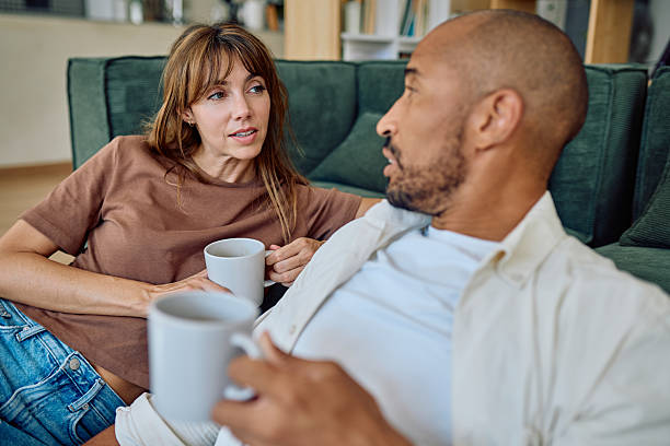 istock Couple relaxing on sofa, enjoying conversation and drinking coffee 2235775130