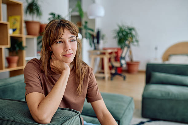 istock Serene Woman Relaxing on Sofa at Home, Contemplating with a Calm Expression 2235775414