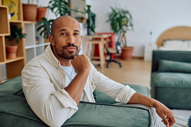 istock Confident man sitting on sofa at home looking relaxed 2235775421