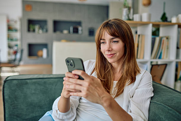 istock Woman using smartphone relaxing on sofa at home 2235775470