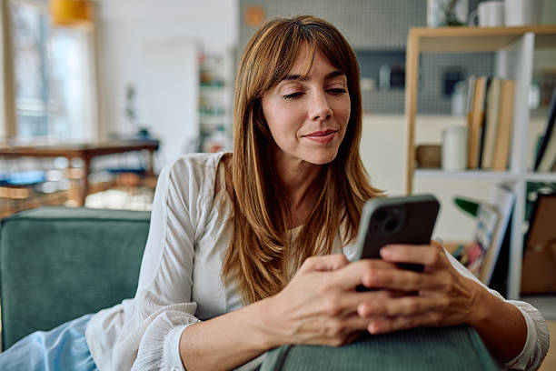 istock Woman using smartphone sitting on sofa at home 2235775471