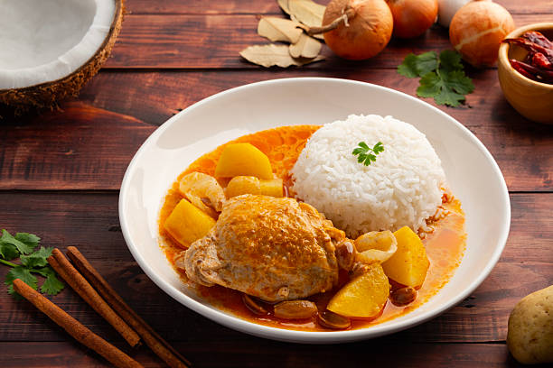 Massaman Curry with chicken and cooked rice in white plate.Cooked chicken meat and potatoes groundnut with massaman curry paste in coconut milk.asian food.