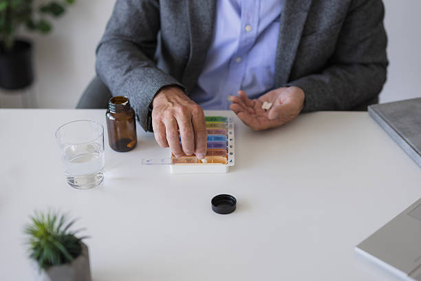 istock Senior man taking medication from pill organizer at home 2235777497