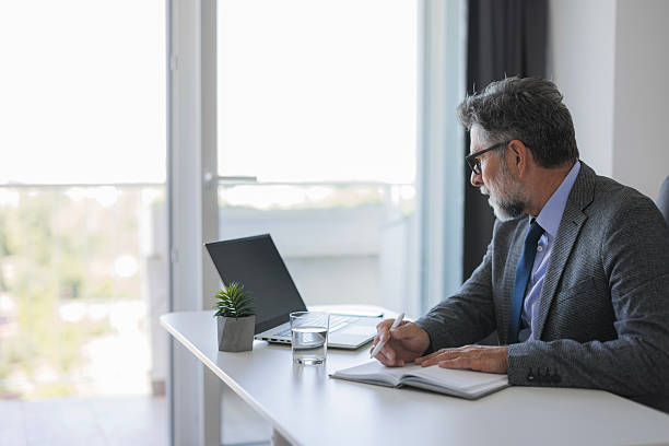 istock Senior businessman taking notes in his modern office 2235778281