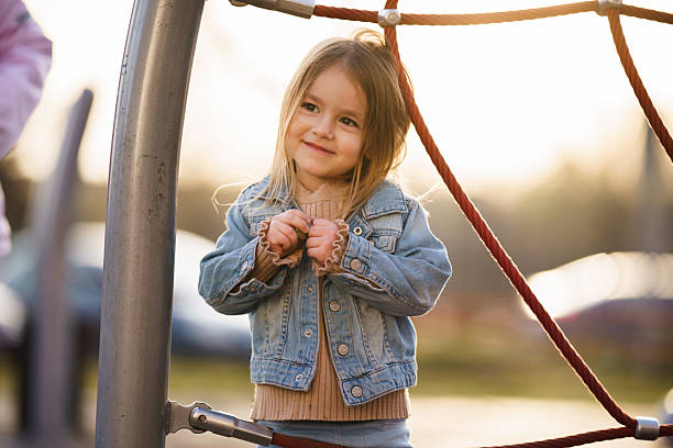 Happy girl playing on climbing frame at playground in a sunny afternoon.