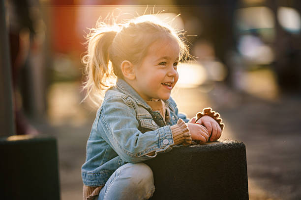 Smiling toddler girl playing at playground during golden hour.