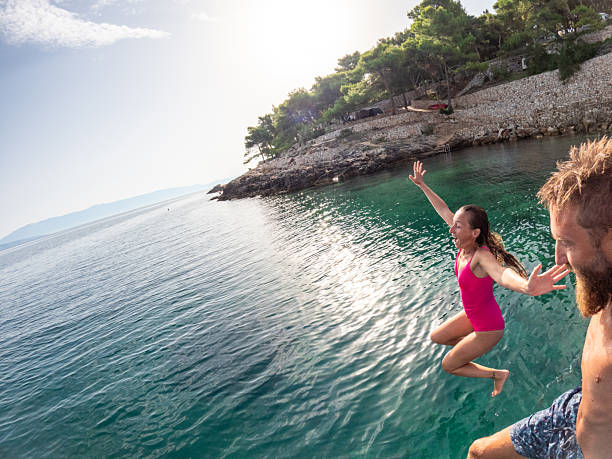 istock Couple Jumping Into Sea from Floating Dock 2235780420