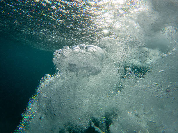Underwater view of a wave with bubbles, light and sand