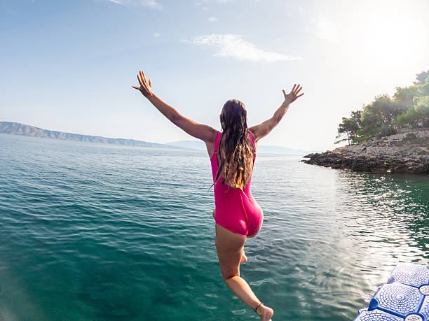 istock Woman Jumping into Ocean from Dock 2235780667