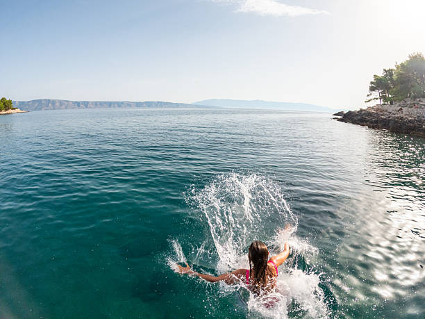 istock Woman Jumping into Ocean from Dock 2235780715